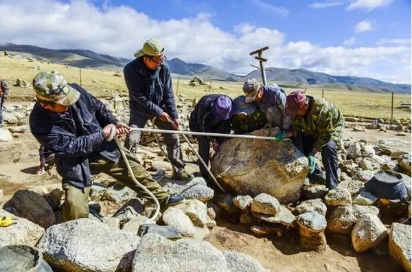 考古学者与当地的工人一起搬开遗址上的一块巨石。（新华社记者 沈桥摄）